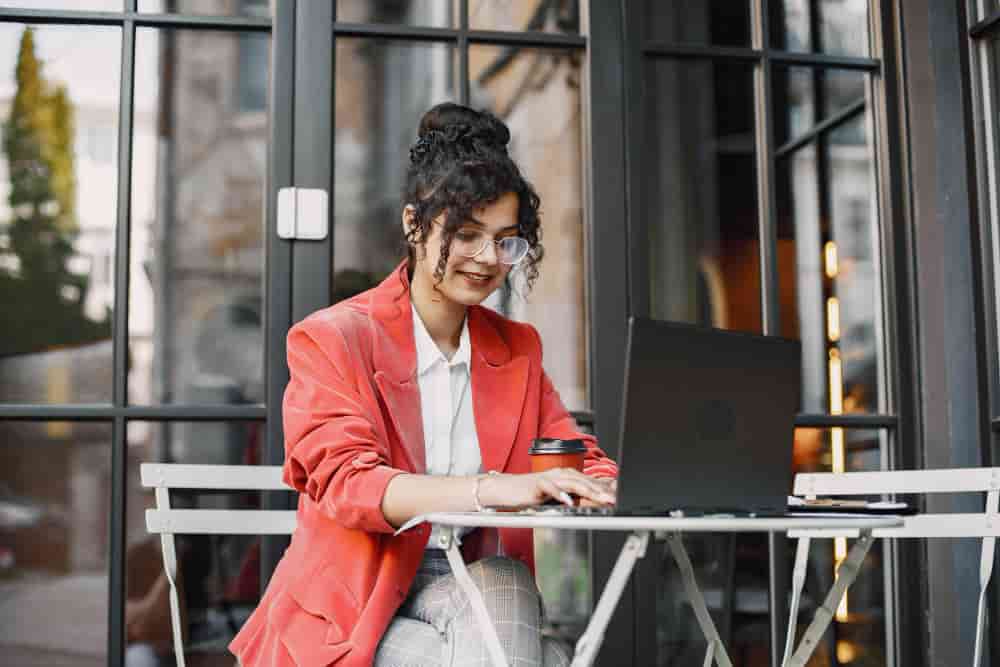 indian woman working laptop street cafe wearing stylish smart clothes jacket glasses min - Women Entrepreneurship in Social Media in General