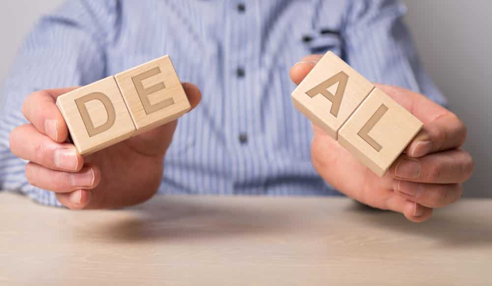 Wooden blocks of DEAL that shows Joint venture termination agreement and cancellation of deal.