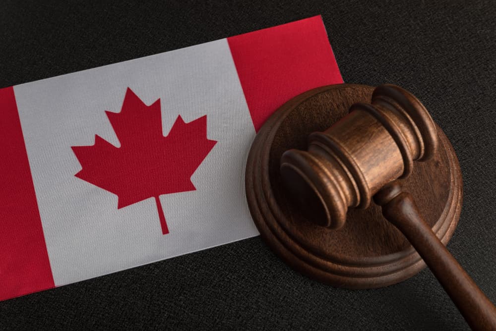 A wooden hammer and canada flag in 
a court ruling on refugees deportation from Canada