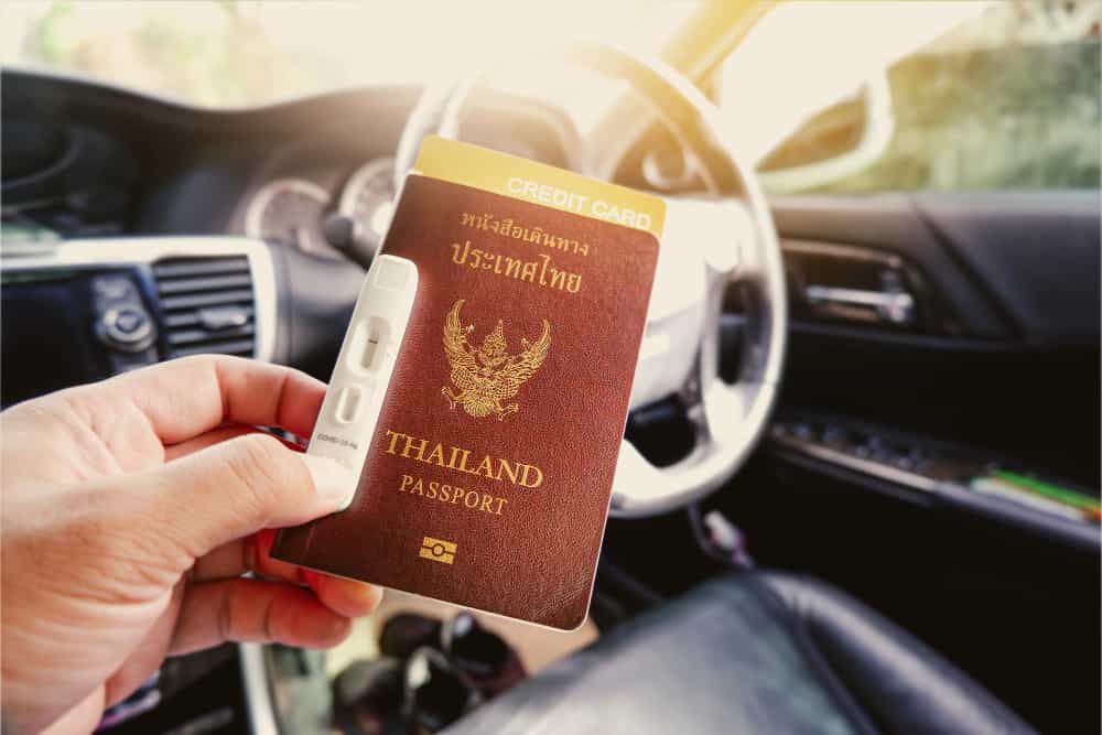 tourist hand holding thailand passport credit card covid19 negative test tape hand with sunlight min 1 - Immigrate to Thailand in General