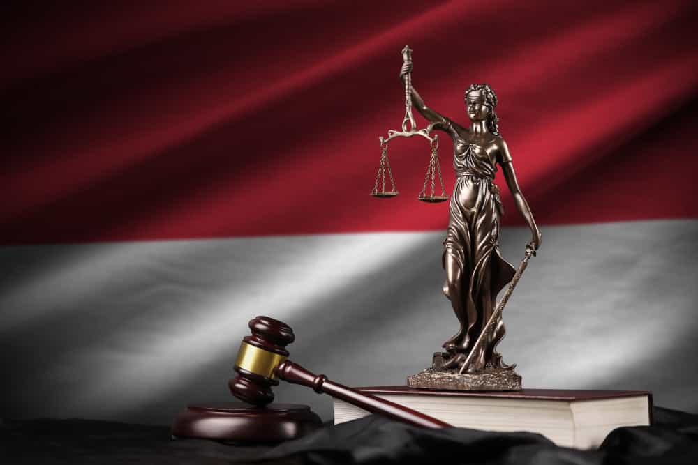 A lady of justice, wooden hammer with Indonesia flag behind it
