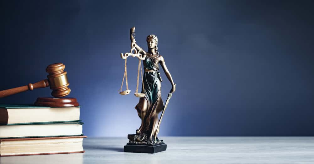 A wooden hammer and books with lady of justice