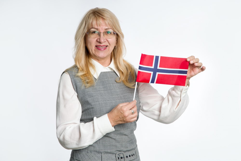 A women in grey sweater holding a norway national flag