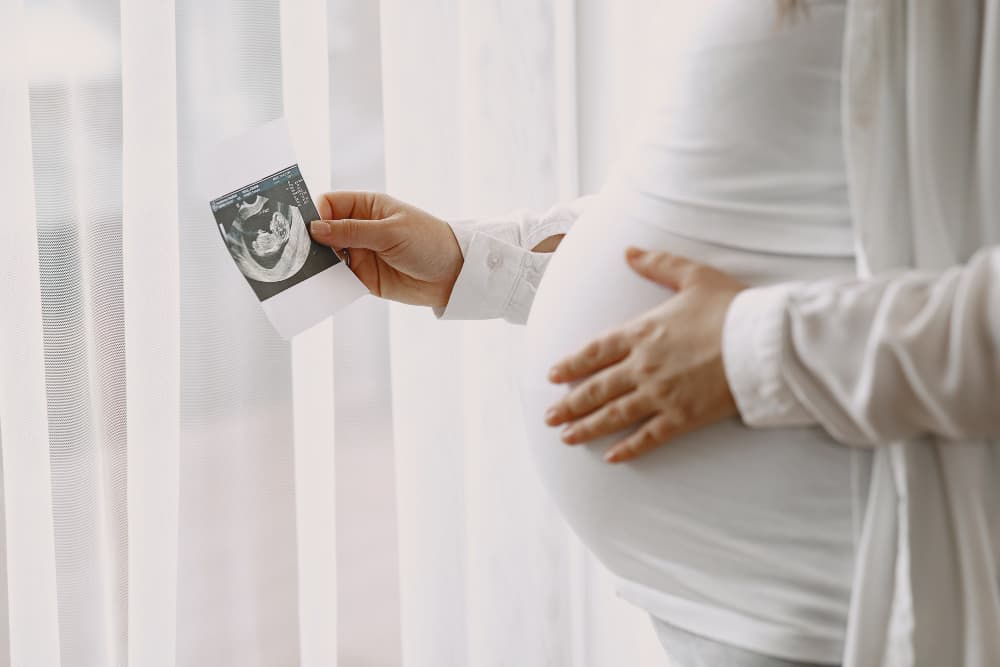 A pregnant woman holding a photo 