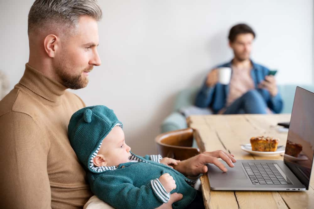 A father working on his laptop while taking care of his child