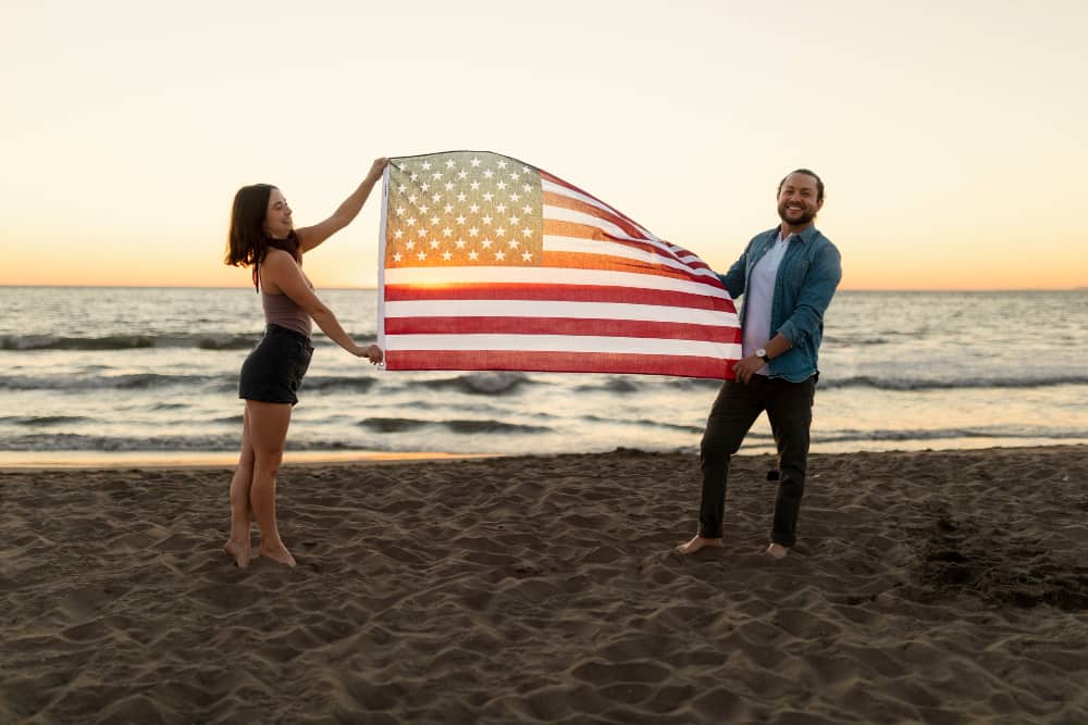 A man and woman holding a US national flag