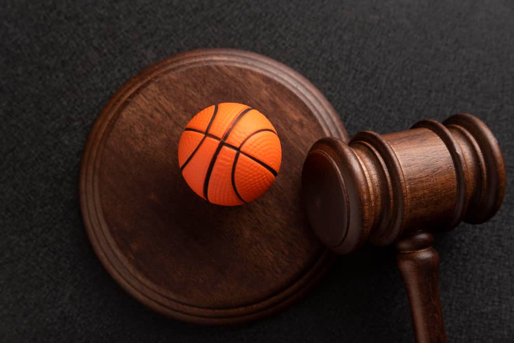A football placed on wooden hammer and a stand in a court trying a case on Sports Law in the USA