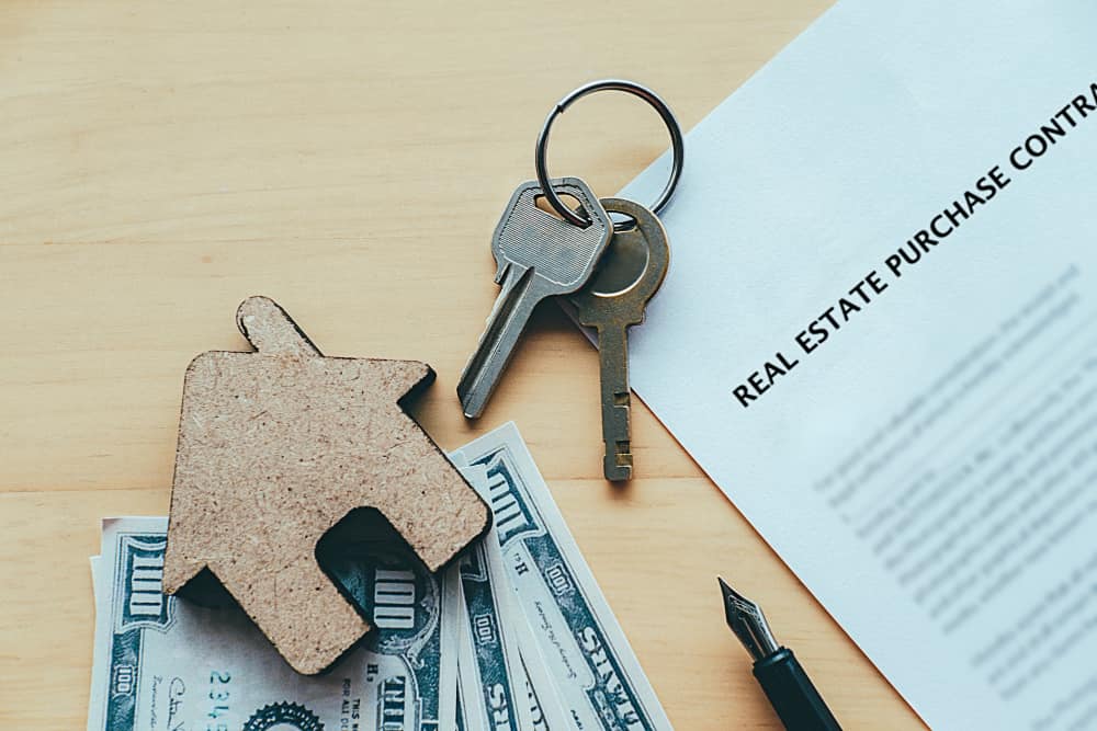 Real Estate Contracts kept on a table with keys and money